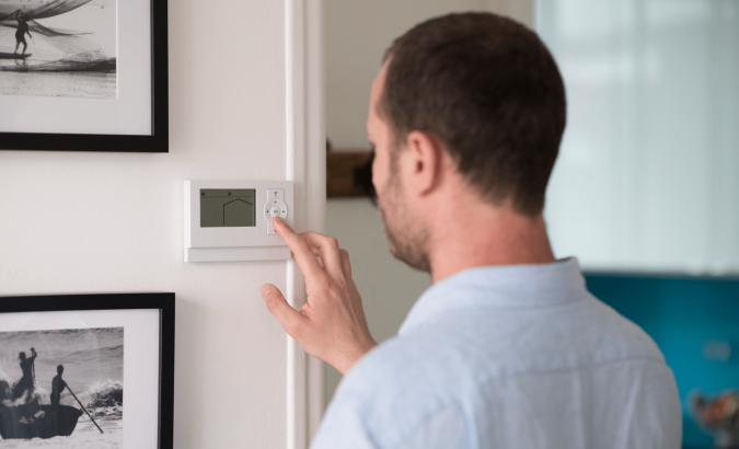 image illustrant un homme contrôlant le thermostat de sa maison