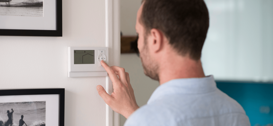 image illustrant un homme contrôlant le thermostat de sa maison